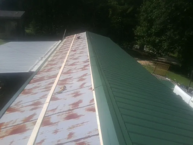 Old rusted panels beside newly installed green metal roofing — Wind Damage Roof Repair by Roofing Brothers in Goodhue