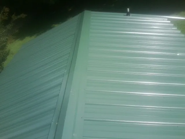 New green metal panels meeting at the ridge of a roof — Flat Roof Repair work by our crew in Goodhue