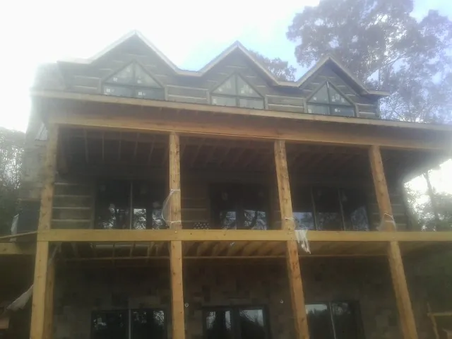 Dormers and porch framing on a large log home under construction — Roof Coating work by our crew in Goodhue