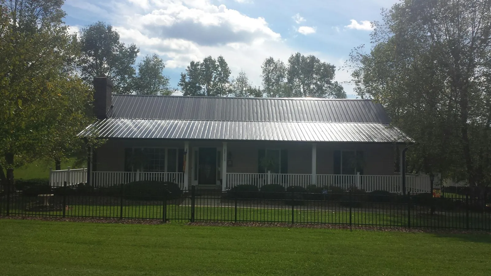 Gray metal roof on a brick ranch with a full width front porch — Gutter Guard Installation work by our crew in Goodhue