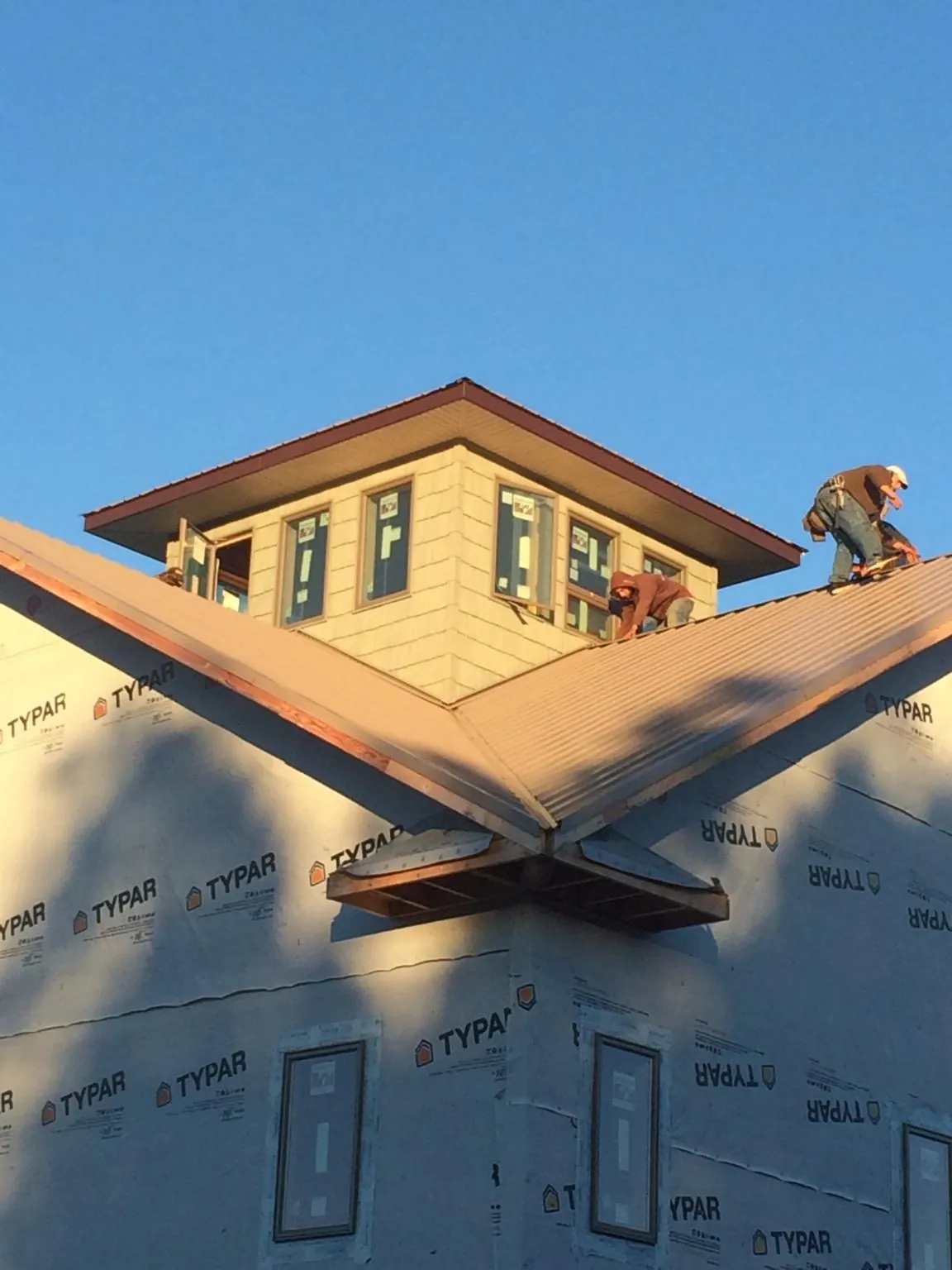 Roofers working around a rooftop cupola on a new metal roof at sunset — Roof Waterproofing in Goodhue by Roofing Brothers